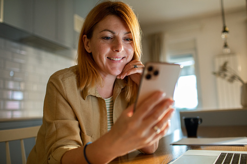 Close up of a mid adult woman using a smart phone at home