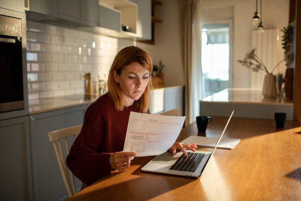 istock Young woman going over her finances at home while using her laptop 1512574815