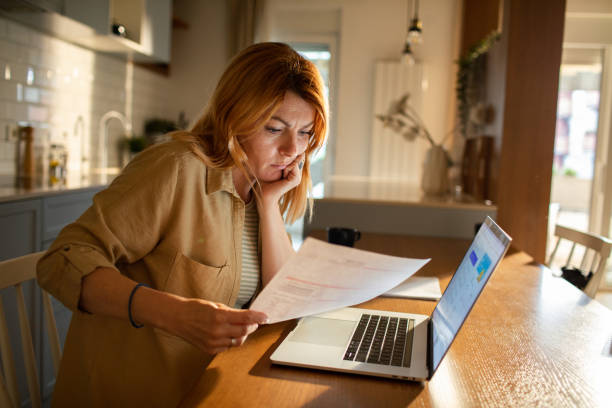 istock Young woman going over her finances at home while using her laptop 1512576466
