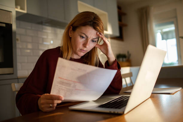 istock Young woman going over her finances at home while using her laptop 1512581560