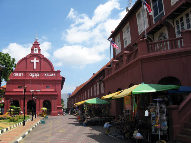 christ church melaka in downtown melaka or malacca. it is an 18th century dutch built anglican church in a bright red as were many dutch buildings of the period. it is a popular tourist destination in malaysia. souvenir stalls can be seen on the right. - cyclo cross imagens e fotografias de stock