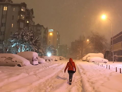 A woman trying to walk on a snowy night in Istanbul, Turkey.