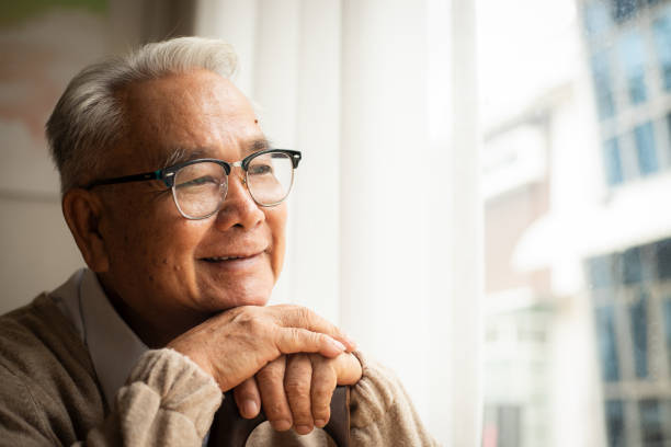 istock Satisfied old man looking outside and smiling while sitting near the window 1512753480