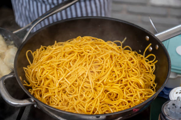Spaghetti cooking in a giant pan outside. Spaghetti noodles cooking in a giant pan outside. large pasta pot stock pictures, royalty-free photos & images