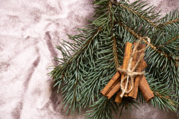 cinnamon lies on branches of a Christmas tree on a pink tablecloth on the table, New Year's
