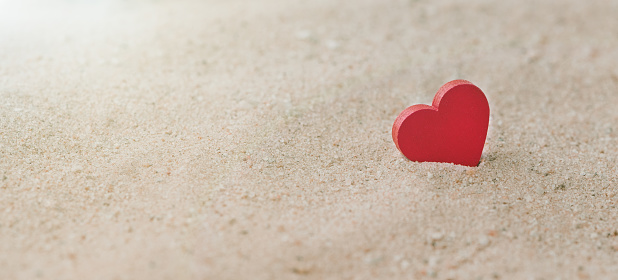 One Wooden Red Hearts On a sandy beach With a Sunlight, The Concept of Love and Couple. Valentine's Day Concept