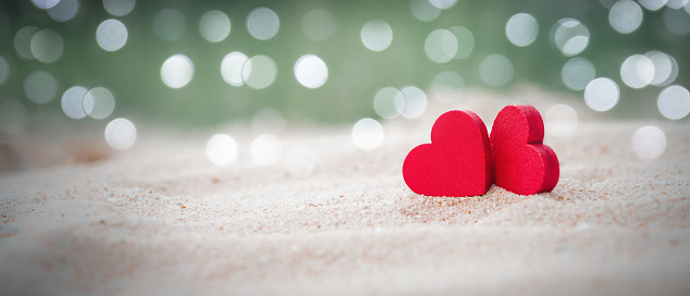 Two Wooden Red Hearts On sandy beach With Light Bokeh, The Concept of Love and Couple. Valentine's Day Concept