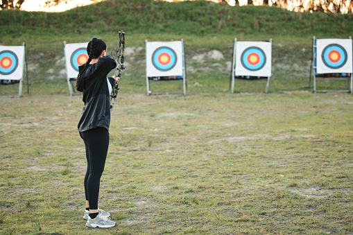 Sports, archery target and bow and arrow training for archer competition, athlete challenge or girl field practice. Shooting, objective and competitive woman focus on precision, aim or outdoor mockup