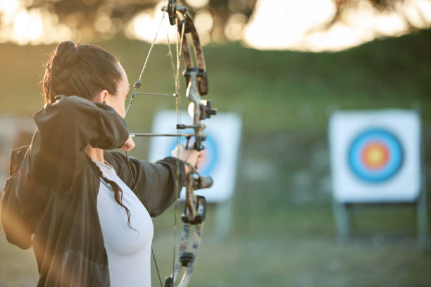 istock Sports archer, target and bow and arrow training for archery competition, athlete challenge or girl field practice. Shooting, objective and competitive woman focus on precision, aim or mock up 1512944614