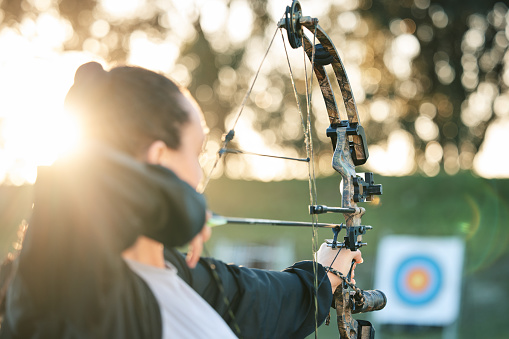Archer training, target and bow and arrow practice for outdoor archery, athlete challenge or girl field competition. Shooting goals, talent and competitive woman focus on precision, aim or objective