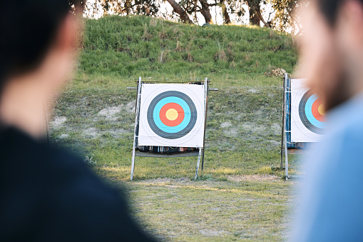 Target, archery coach or bow and arrow learning for archer competition, athlete challenge or girl training practice. Sports teacher, teaching talk or man coaching woman on precision, aim and shooting