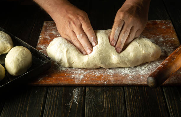 istock The baker's hands knead the dough before baking the buns. Work environment on the kitchen table in the bakery 1512971844