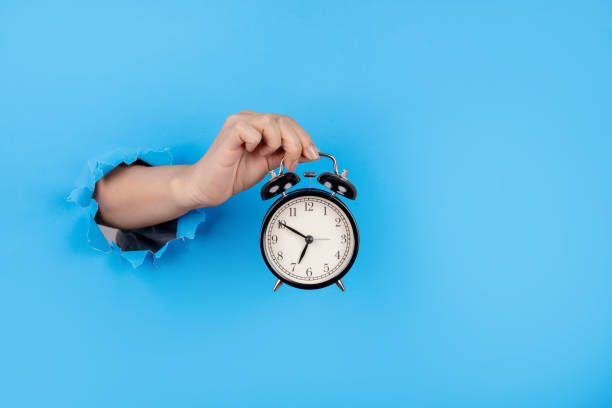 istock Female hand holding alarm clock through paper background. 1513033177