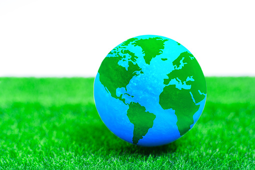 Miniature globe set on a verdant green lawn. Eco-consciousness, sustainable development and promotion of a shared responsibility for Earth's well-being.