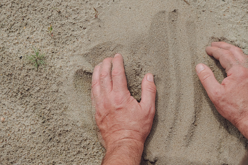 The clean sand. Strong male hands. Copy space.