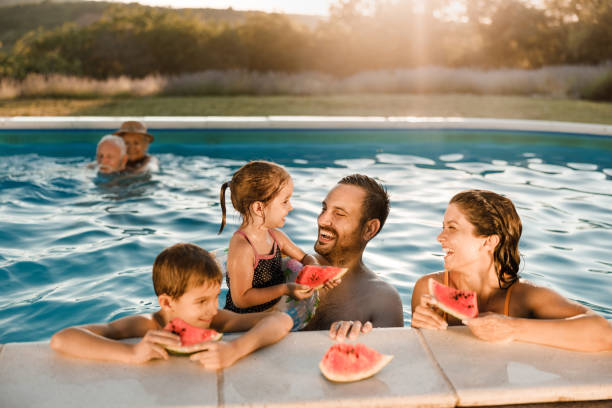istock Happy family talking while eating watermelon in the pool. 1513088691