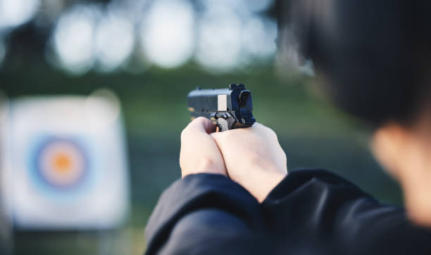 istock Hands, gun and aim at shooting range target with weapon outdoor for security training. Person learning defence for safety and focus for sport competition or game with handgun gear and bullseye board 1513104573