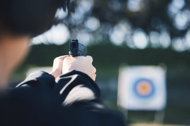firearm, target and person training outdoor at shooting range for game exercise or sports challenge closeup. man hands with gun, circle and aim for practice, police academy or field practice mission - playing field determination exercising relaxation exercise imagens e fotografias de stock