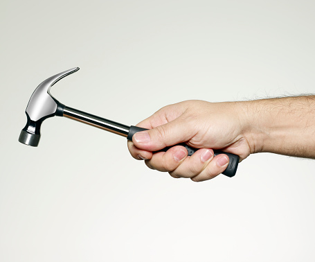 A strong male hand is holding a metal quality hammer.