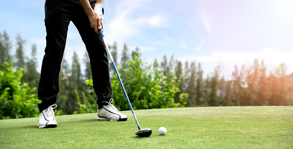 Male golfer playing golf on golf course. Golfer uses a driver to hit a golf ball from the fairway.