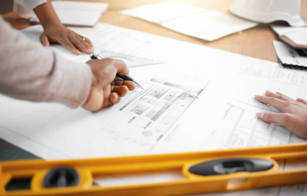 istock Hands, collaboration and planning with an architecture team working in their office on design from above. Teamwork, construction or blueprint with an architect, designer and engineer at work together 1513191422