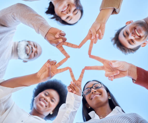 istock Star, low angle or happy team with peace sign, diversity or community collaboration with blue sky. Portrait, smile or group of people smiling with support, solidarity or motivation together outdoors 1513191960