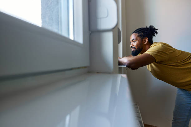 istock Smiling black man looking through window from his home. 1513199848