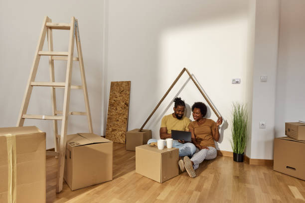 istock Happy black couple using laptop on a break from unpacking at new home. 1513205880