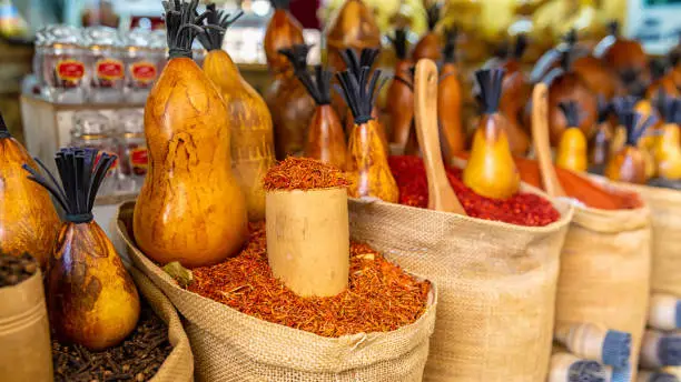 Bags full of various multicolored spices and traditional wooden saltshaker as souvenir on a market stall. Bukhara, Uzbekistan, Central Asia