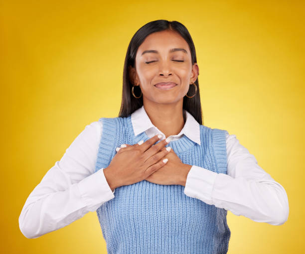 istock Gratitude, peace and young female in a studio with her hand on her chest for a grateful expression. Mindfulness, smile and Indian woman model with thankful gesture isolated by yellow background. 1513237310