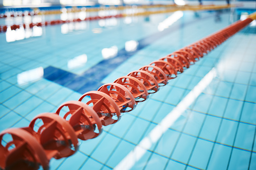 Water, empty swimming pool and lanes for competition, exercise and workout. Sports, swim and fitness with lane ropes or divider in liquid for aquatic training, exercising or underwater practice.
