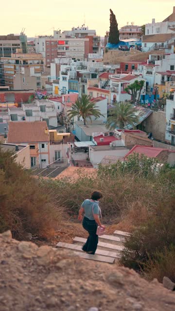 Woman walking down a staircase with the city of Alicante in the background