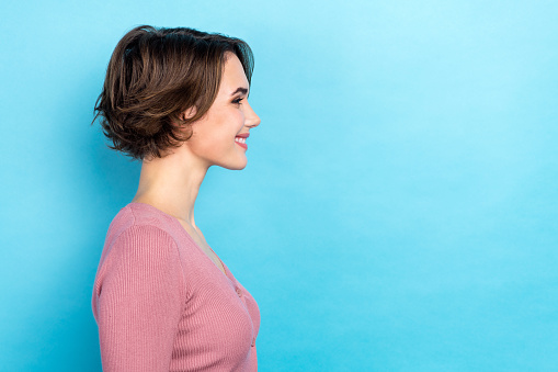 Profile portrait of satisfied glad lovely lady beaming smile look empty space isolated on blue color background.