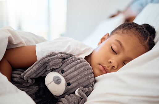 Peace, morning and wellness of black child sleeping in cozy bed with toy teddy in home on the weekend. Relax, sleep and health of kid dreaming in comfortable home bedroom with teddy bear.