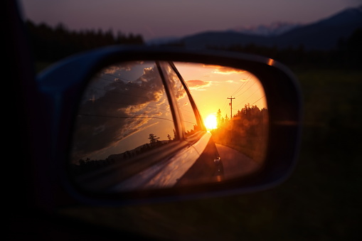 Beautiful sunset in sideview car mirror on mountain road