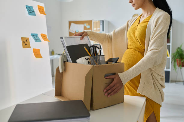 Pregnant businesswoman packing her things in box stock photo