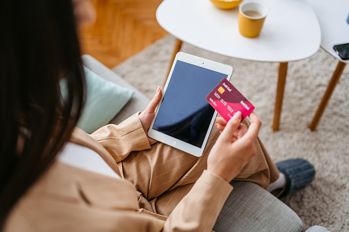 Young woman shopping online using digital tablet at home.