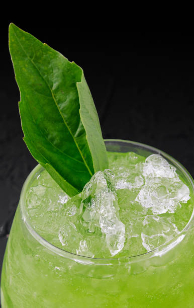 istock Glass with green cocktail with ice on black 1513406800
