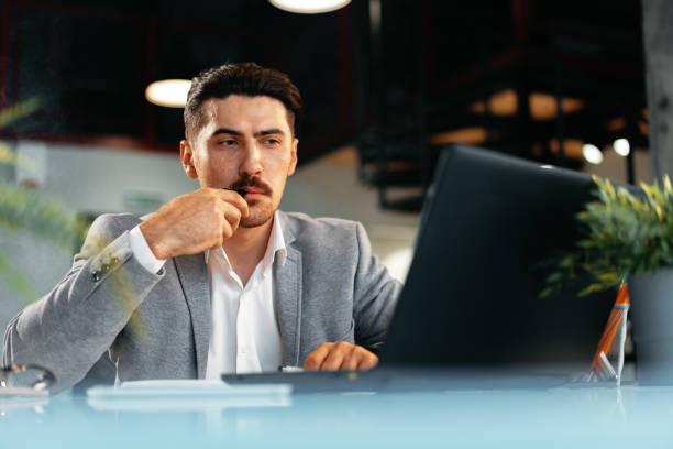 istock Young businessman smoking an electronic cigarette in his office while working 1513413688
