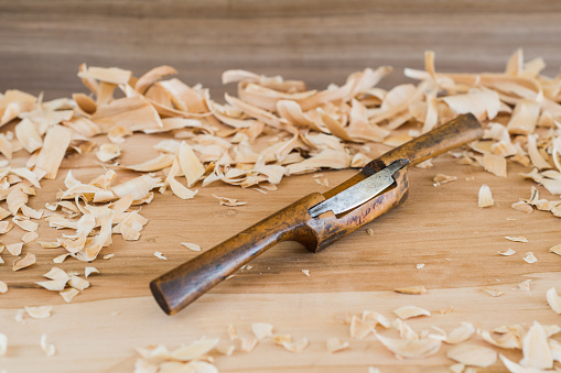 Old wooden spokeshave for woodworking with wood shavings.