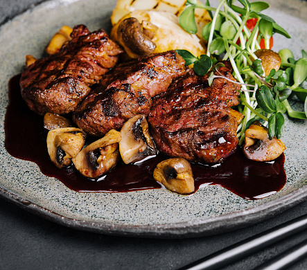 Rare roasted thick juicy beef fillet medallion topped with braised mushrooms and seasoned with fresh herbs