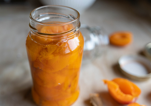 Stewed apricots in a glass jar on kitchen counter. Ready to get canned. Closeup, front view