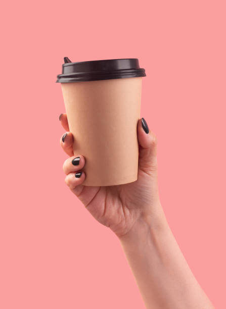 istock Woman's hand holding disposable coffee cup on pink background 1513489974