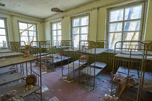Room full of empty metal bed frames in abandoned kindergarten