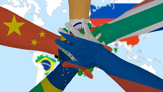 BRICS, five hands, with the flags of the countries, come together to form an economic group