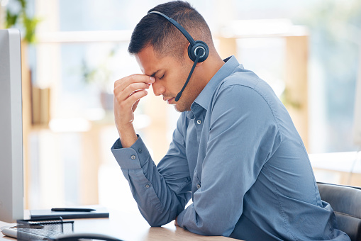 Headache pain, tired or man in call center with burnout feeling overworked in crm communication. Migraine, office or stressed telemarketing sales agent with anxiety, fatigue or mental health problems