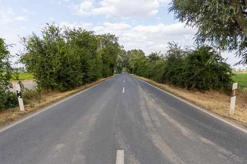 Side view of empty asphalt road and green field.