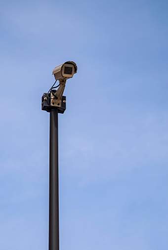 Camera on the public road. Surveillance with security cameras on the street for the safety of citizens with a background of blue sky with fluffy clouds.