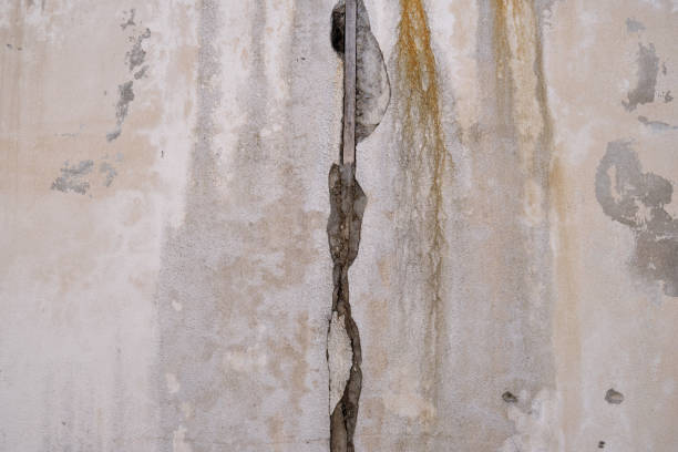 Close up of a red cracked surface with a vertical split showing concrete underneath