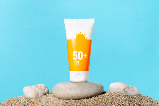 Sunscreen in an orange tube on blue background with beach sand, copy space. Summer beach, vacation concept, spf uv-protect cosmetics